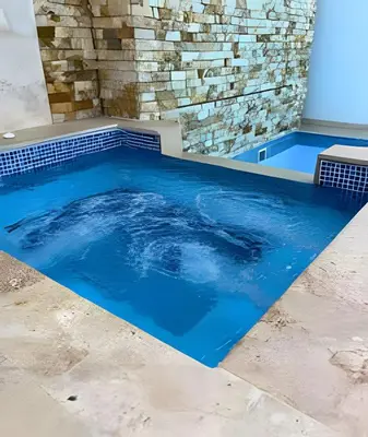 a swimming pool with blue water in front of a stone wall at Bay View Duplex in Bocagrande in Cartagena de Indias