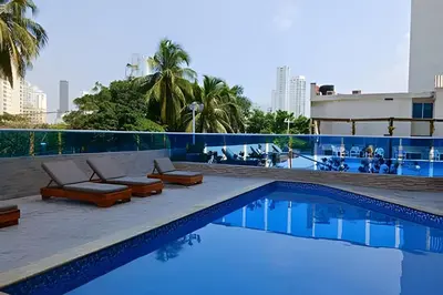 a swimming pool with lounge chairs and a building at Apto a pasos de la playa, ubicación perfecta in Cartagena de Indias