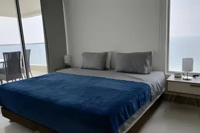 a bedroom with a blue bed and a desk and window at Espectacular vista en la mejor zona del Laguito in Cartagena de Indias