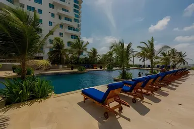 a row of lounge chairs next to a swimming pool at Precioso apto cama King y con salida a playa in Cartagena de Indias
