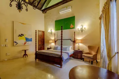 a bedroom with a bed and a chair and a table at Estrella de San Pedro B&B in Cartagena de Indias