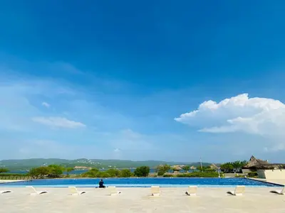 a person sitting on a beach next to a swimming pool at Cabaña frente al mar in Tubará