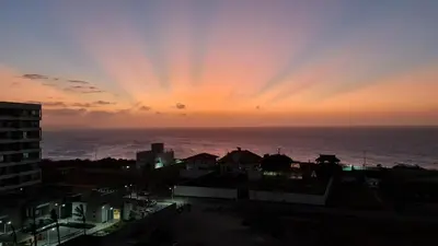 a sunset over the ocean with a city at De Luxe acogedor con vistas al Mar y Atardeceres in Maizal