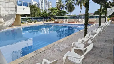 a swimming pool with white lounge chairs next to it at Apartamento con vista al Laguito, Nuevo Conquistador in Cartagena de Indias