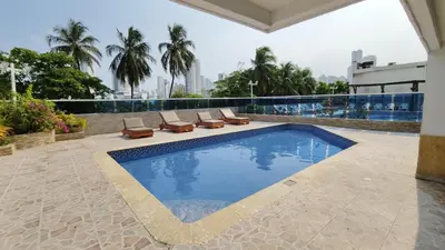 a swimming pool with lounge chairs on a building at Apartamento con vista al Laguito, Nuevo Conquistador in Cartagena de Indias