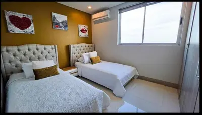 a bedroom with two beds and a window at Oceanview Suite with two Pools, Gym & Guest Access in Cartagena de Indias