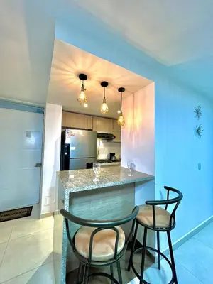a kitchen with two bar stools and a counter at Luxury Apartament With Pool in Barranquilla