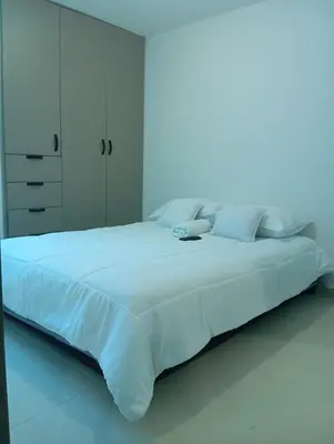 a large white bed in a white bedroom with a light at Apartamento moderno en norte de la ciudad in Barranquilla