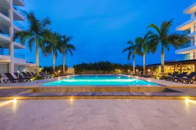 a swimming pool with palm trees and a building at Sonesta Apartamento en Cartagena in Cartagena de Indias