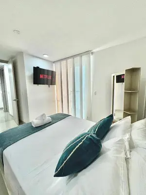 a bedroom with a large white bed with blue pillows at Lujoso alojamiento empresarial en Cartagena in Cartagena de Indias