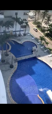 a large blue swimming pool with palm trees and a building at Tu lugar favorito en Cartagena in Cartagena de Indias