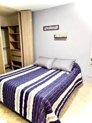 a bedroom with a bed with a blue and white striped blanket at Apartamento con Vistas a la Ciudad in Barranquilla