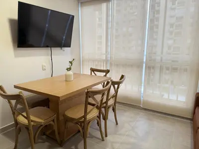 a dining room table with chairs and a television on a wall at APTO LODGE - Confortable y acogedor apartamento al norte de Barranquilla vía a Puerto Colombia in Barranquilla