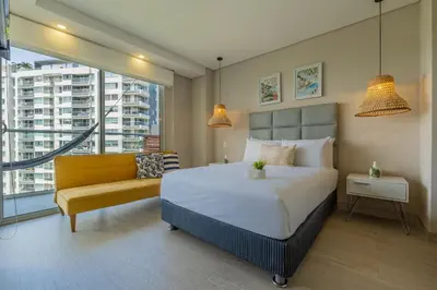 a bedroom with a large bed and a yellow couch at MQ903 | Jacuzzi & hamaca · Vista espectacular in Cartagena de Indias