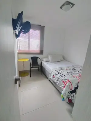 a bedroom with a bed and a chair and a window at Sol y Brisa 811 in Cartagena de Indias