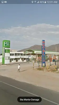 a man walking down a street in front of a gas station at Casa Hotel Marly in Santa Marta