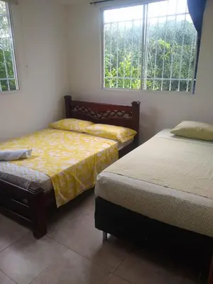 a bedroom with two beds and two windows at Casa Hotel Marly in Santa Marta