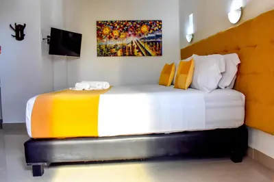 a bedroom with a large bed with a painting on the wall at Hotel Casa Tere in Cartagena de Indias