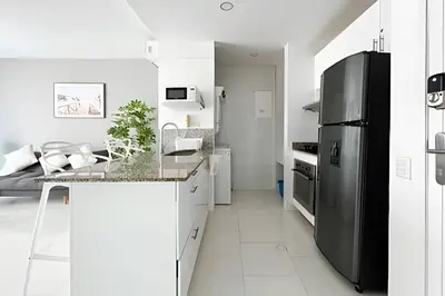 a kitchen with a stainless steel refrigerator and white cabinets at 1 Dormitorio y terraza Morros. Vista mar in Cartagena de Indias