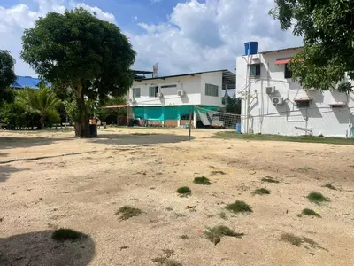 a dirt field in front of a building with a tree at Habitaciones Melany in Coveñas