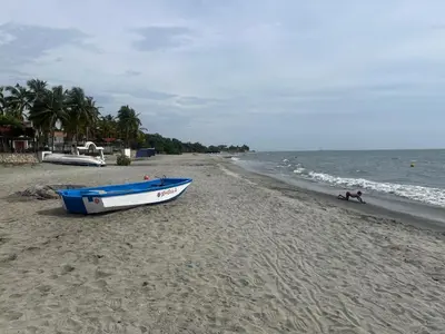a boat sitting on a sandy beach next to the ocean at Villa Colibrí in Santa Marta