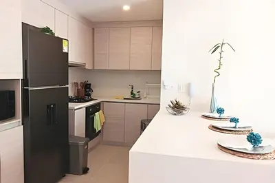 a kitchen with white cabinets and a black refrigerator at “Lujoso Apto con Piscina, Terraza Privada y Salida a la Playa” in Cartagena de Indias
