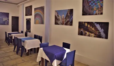 a restaurant with tables and chairs and paintings on the wall at Open Sea Hotel Cartagena - Frente al mar in Cartagena de Indias