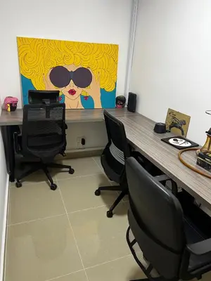 a desk with chairs and a painting of a woman with sunglasses at Duplex Penthouse Rooftop Lounge in Barranquilla