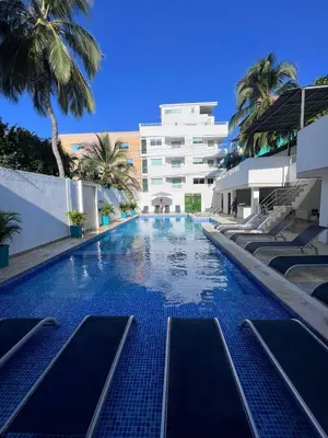 a swimming pool with palm trees and a building at La Boquilla Oasis - Charming 1-Bedroom Apartment with Pool in Cartagena de Indias
