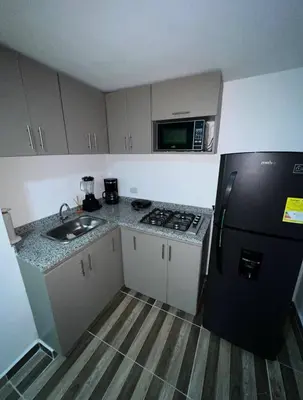 a kitchen with a black refrigerator and a microwave at La Boquilla Oasis - Charming 1-Bedroom Apartment with Pool in Cartagena de Indias