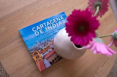 a book sitting on a table next to a vase with a flower at Disfruta el espectáculo de la bahía in Cartagena de Indias