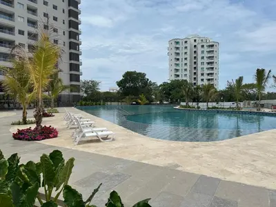 a large swimming pool with lounge chairs and buildings at Apartamento de lujo en Santa Marina Santa Marta in Santa Marta