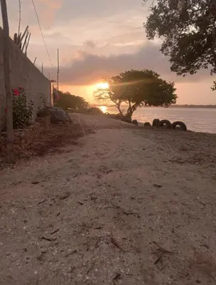 a dirt road next to the water with a sunset at Cabaña Barbacoas in Santa Ana