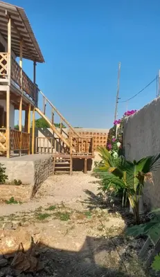a house with a wooden staircase next to a building at Cabaña Barbacoas in Santa Ana