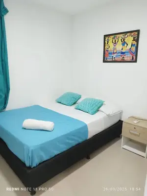a bedroom with a bed with a blue blanket and pillows at Apartamento turístico cerca al mar en Cartagena in Cartagena de Indias