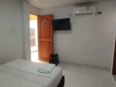 a room with a bed and a television and a door at Casa Turistica Parador Verona in Cartagena de Indias