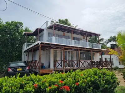 a house with a balcony and a car parked in front at HELENA Beach House in La Rada