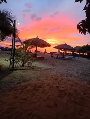 a sunset on a beach with umbrellas and the ocean at Los Clemones in Rincón