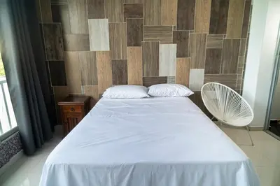 a bedroom with a white bed and a wooden wall at Cartagena Apartamento in Cartagena de Indias