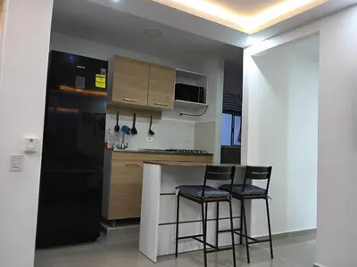 a kitchen with two bar stools and a black refrigerator at Espectacular apartamento amoblado en BARRANQUILLA in Barranquilla