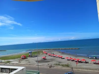 a beach with red umbrellas and the ocean at Apartment near the beach and airport in Cartagena de Indias