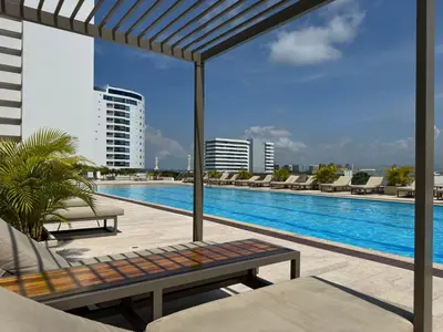 a swimming pool with a bench and chairs on a building at Amazing loft - 2 minutes from the airport! in Cartagena de Indias