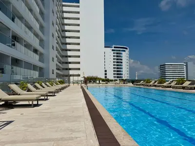 a swimming pool with lounge chairs next to a building at Amazing loft - 2 minutes from the airport! in Cartagena de Indias