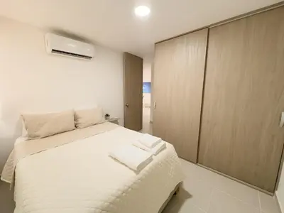 a bedroom with a white bed and a cabinet at 2 cuartos AC y piscina in Cartagena de Indias