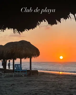 a beach with a straw umbrella and chairs and the ocean at Atardeceres casa de playa in Cartagena de Indias