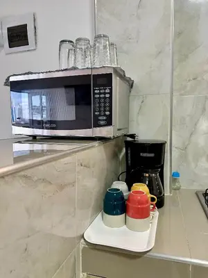 a microwave on a shelf with cups and a coffee maker at Casa Murillo Toro in Cartagena de Indias