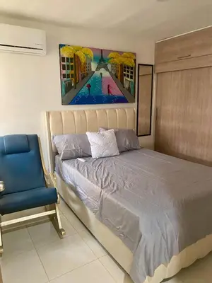 a bedroom with a bed and a blue chair at Apartamento acogedor y económico in Barranquilla