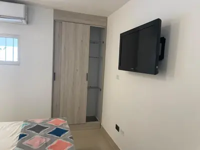 a flat screen tv hanging on a wall in a bedroom at Apartaestudio Barranquilla in Barranquilla
