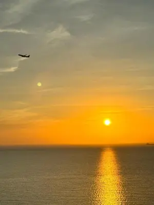 an airplane flying over the ocean at sunset at Maranta Beach in Santa Marta