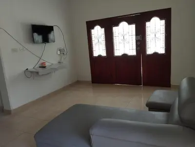 a living room with a couch and a tv and two doors at Casa Ingrid in Coveñas